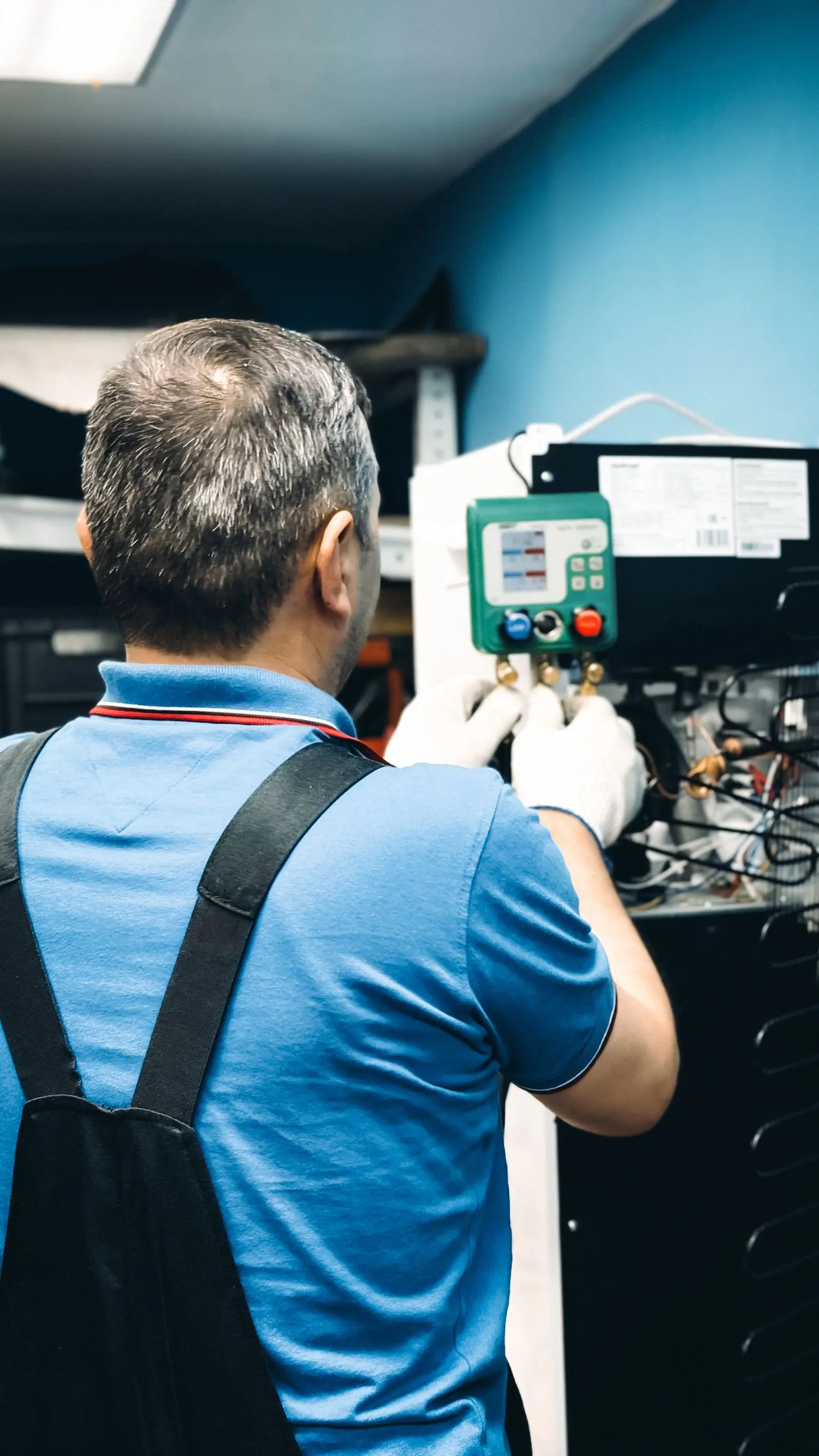 Technician reading refrigerant gauges during AC maintenance