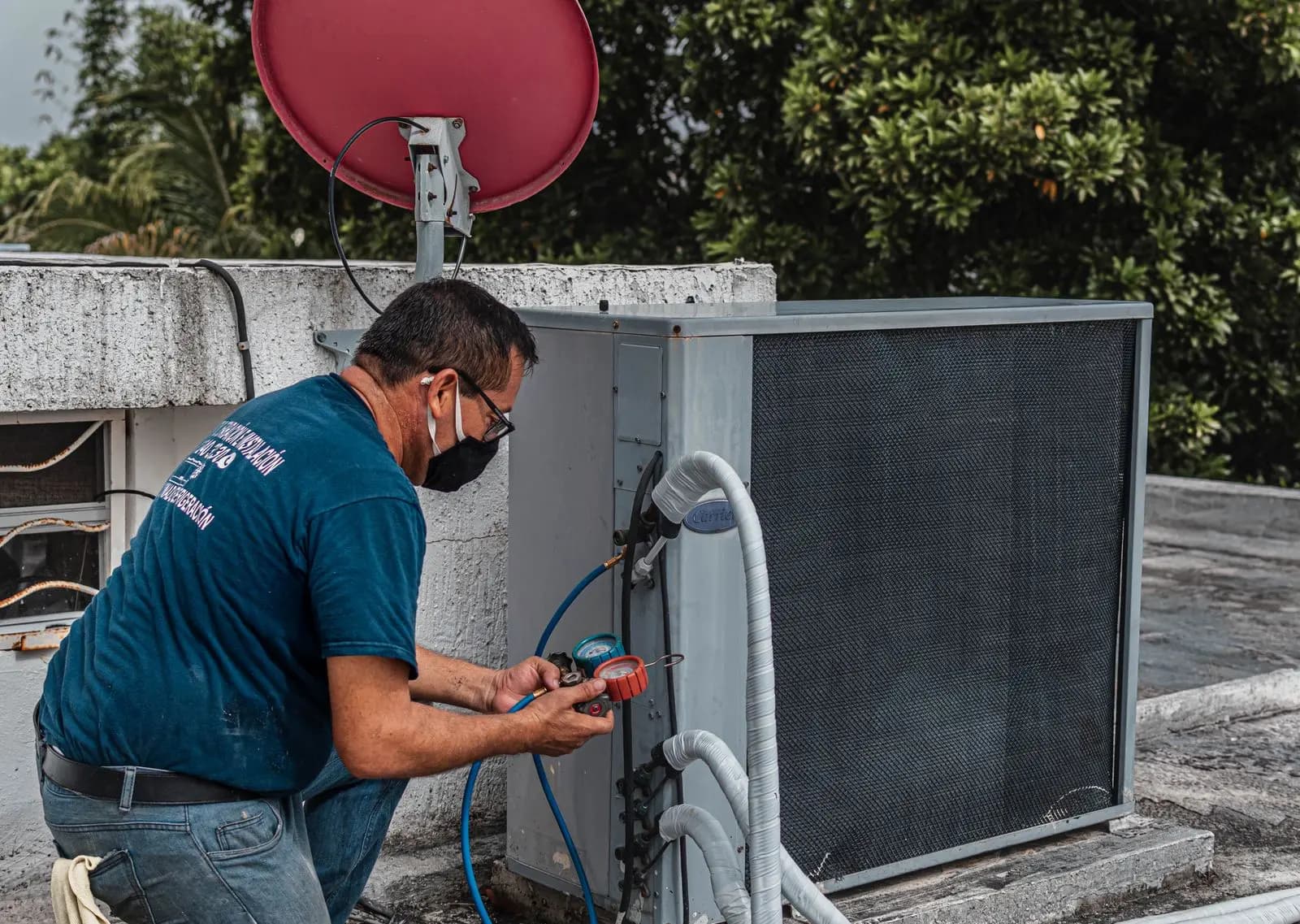 HVAC technician testing a rooftop condenser with gauges