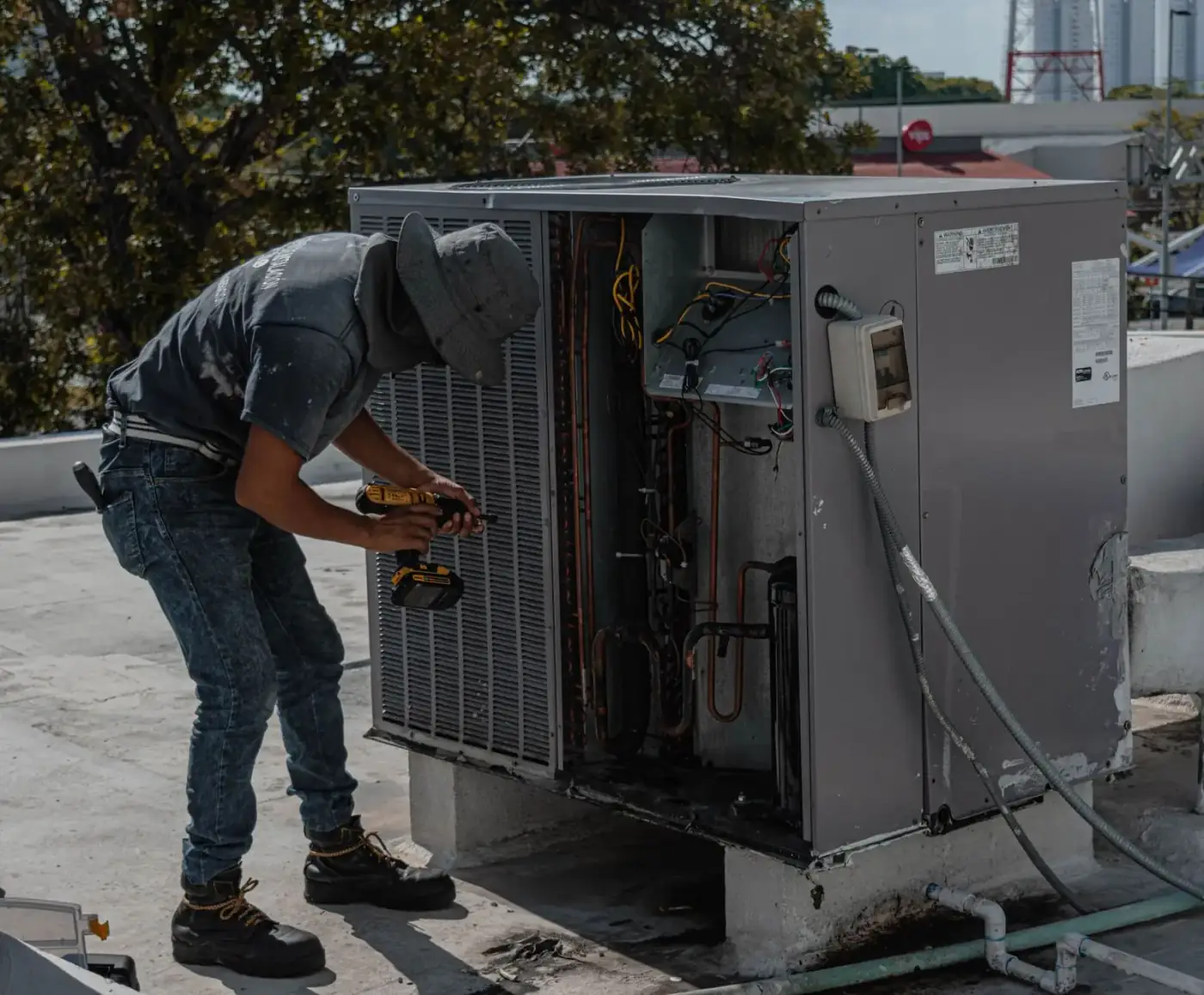 Technician repairing an open rooftop air conditioning unit